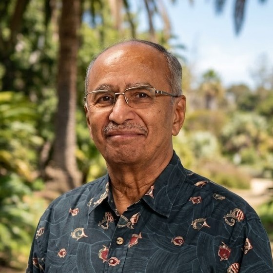 Portrait of Dr. Vinay Vaidya smiling in a sunny garden with palm trees